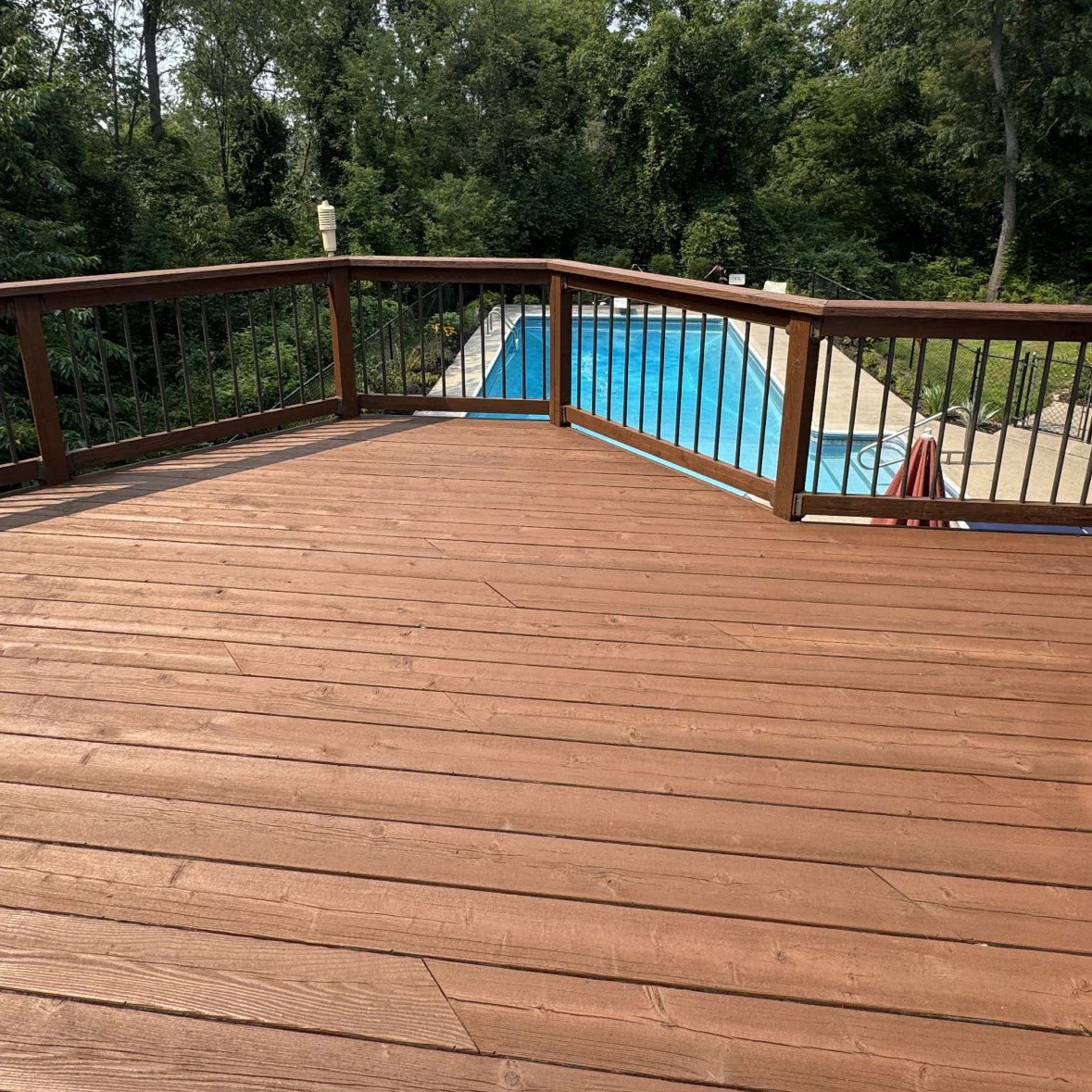 Freshly stained wooden deck by Paint EZ – professional deck and fence staining services that protect and enhance outdoor wood surfaces.