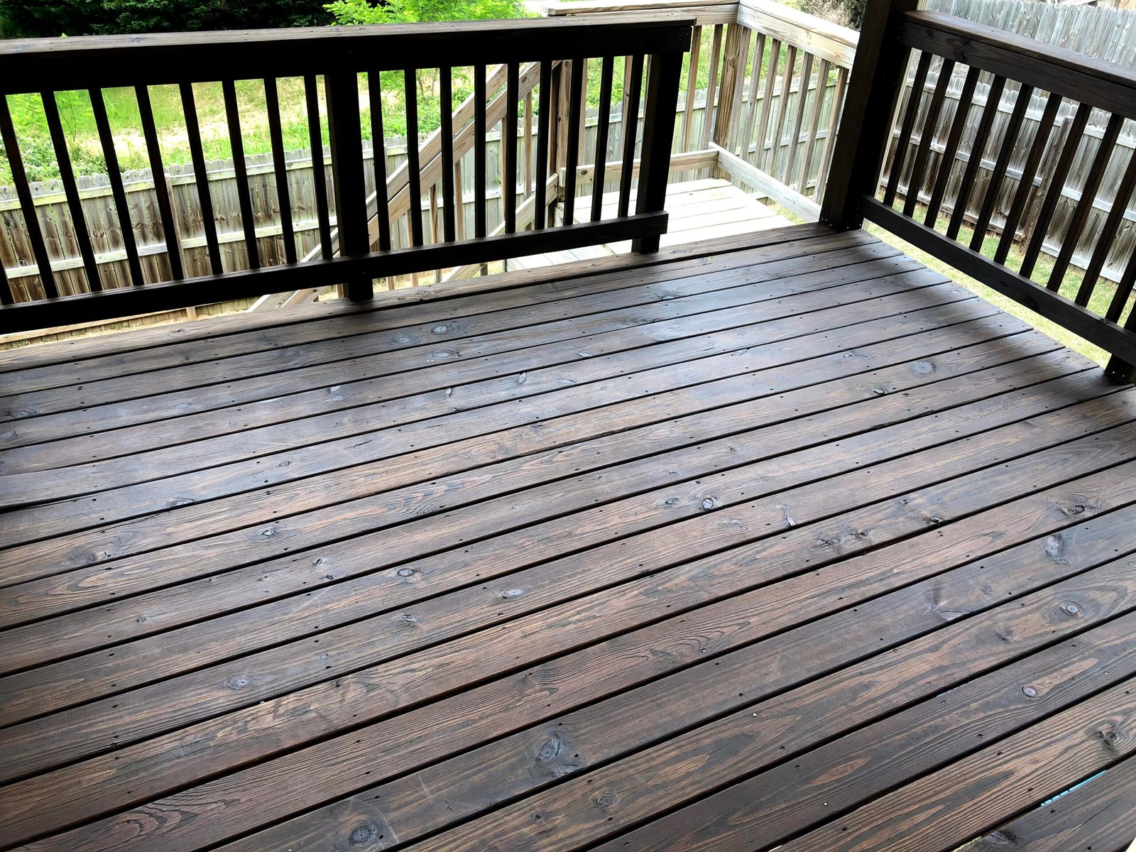 Freshly stained wooden deck by Paint EZ – professional deck and fence staining services that protect and enhance outdoor wood surfaces.