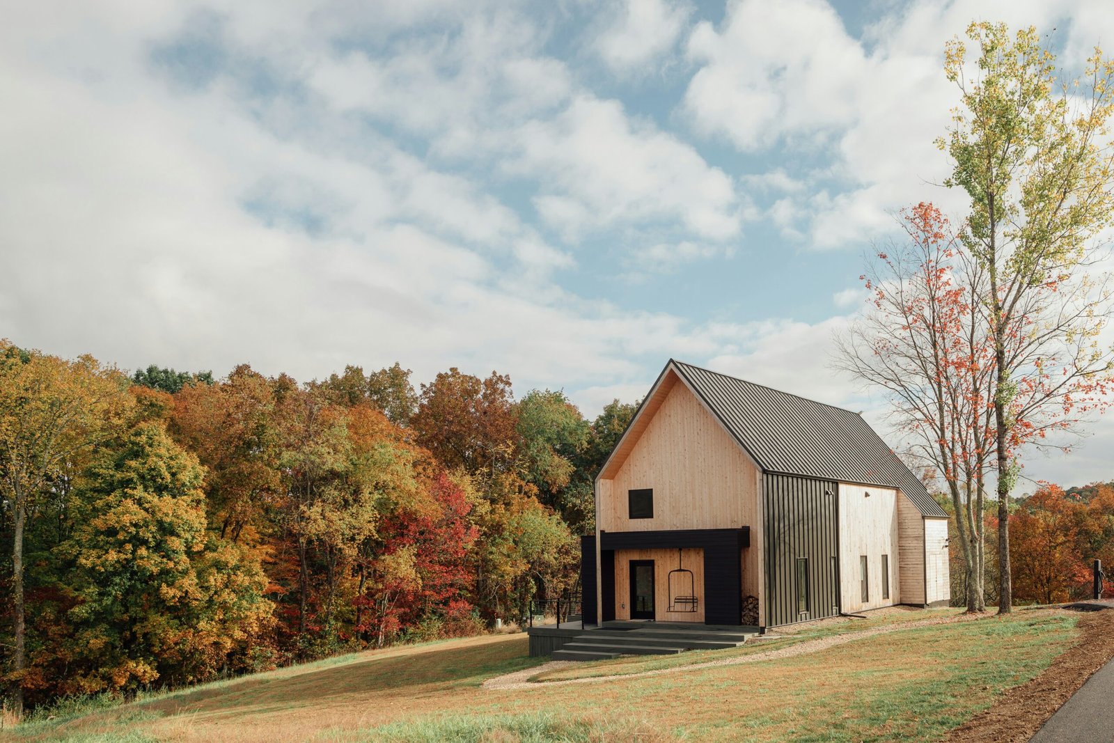 Modern barn-style building combining wood and metal siding in a scenic landscape setting