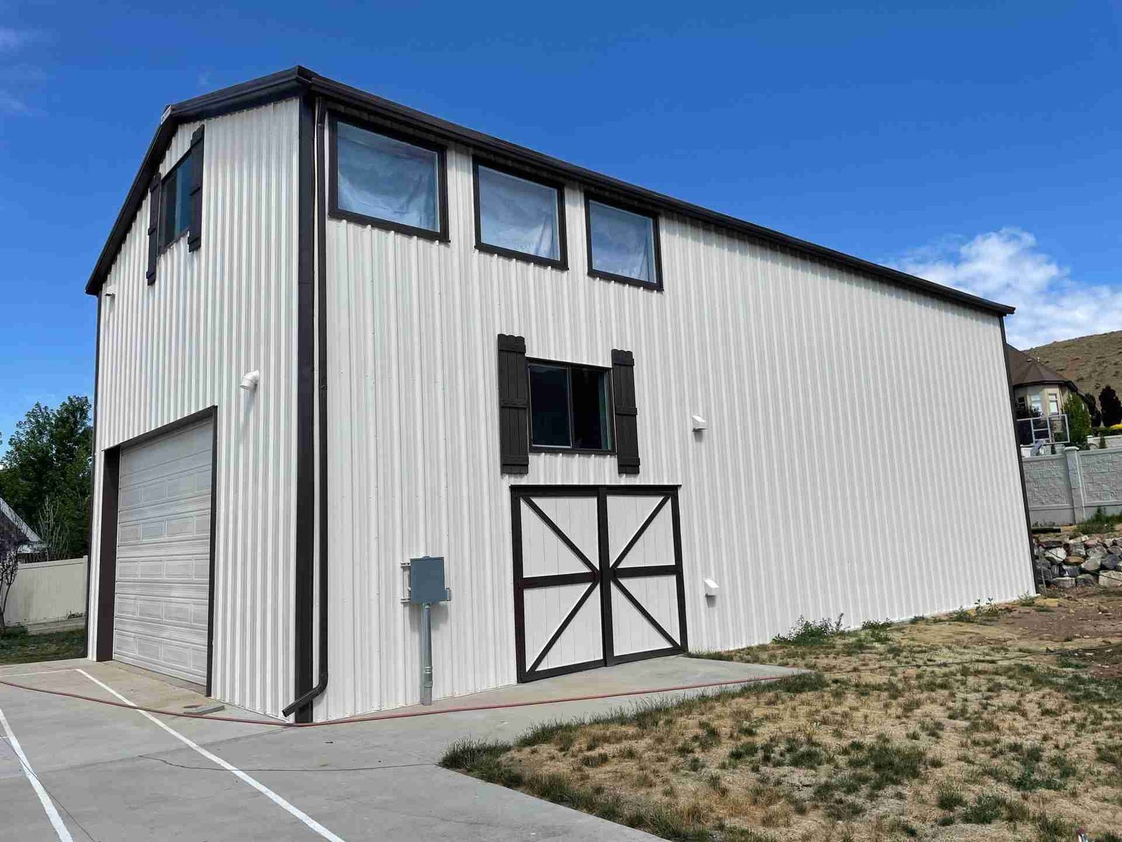 Modern metal barn with white painted siding and black trim showcasing clean exterior finish