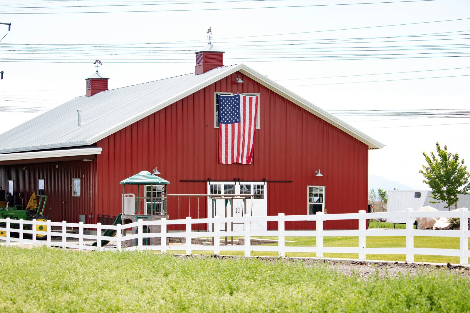 Red painted barn exterior with white trim and American flag on a rural farm property