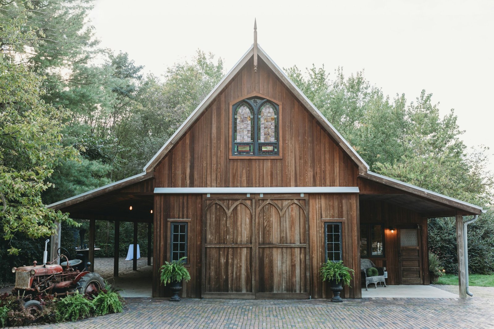 Rustic wooden barn with natural stain finish surrounded by trees and greenery