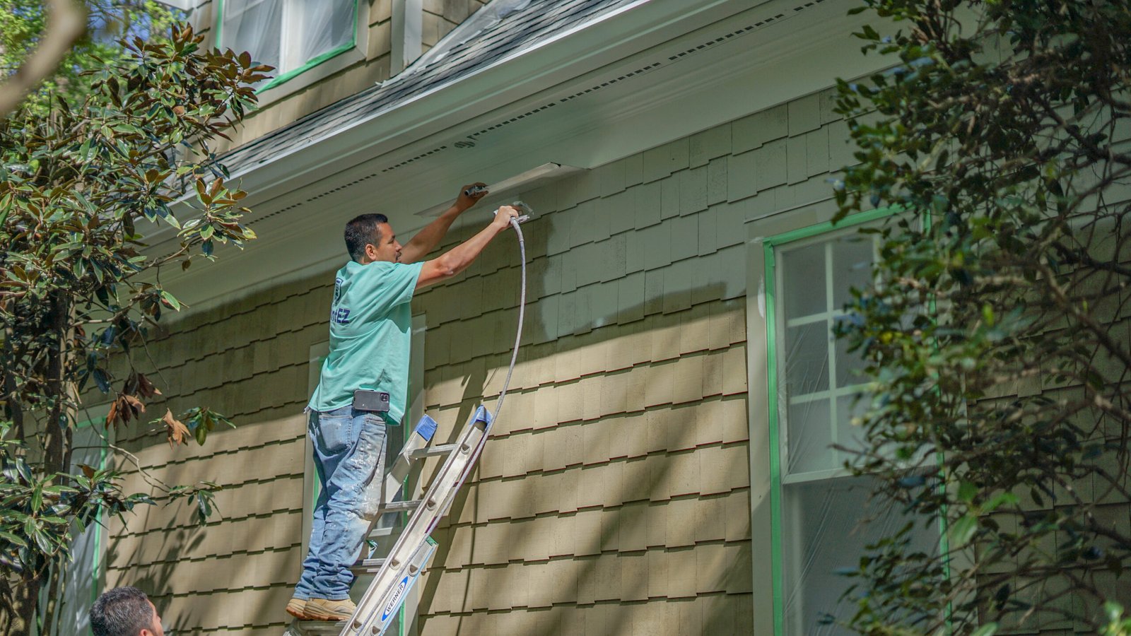Professional Paint EZ painter applying exterior paint to a home, highlighting proper prep work and long-lasting results for increased resale value