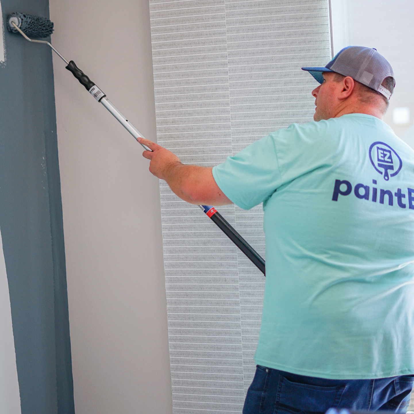Paint EZ painter rolling paint onto an interior wall.