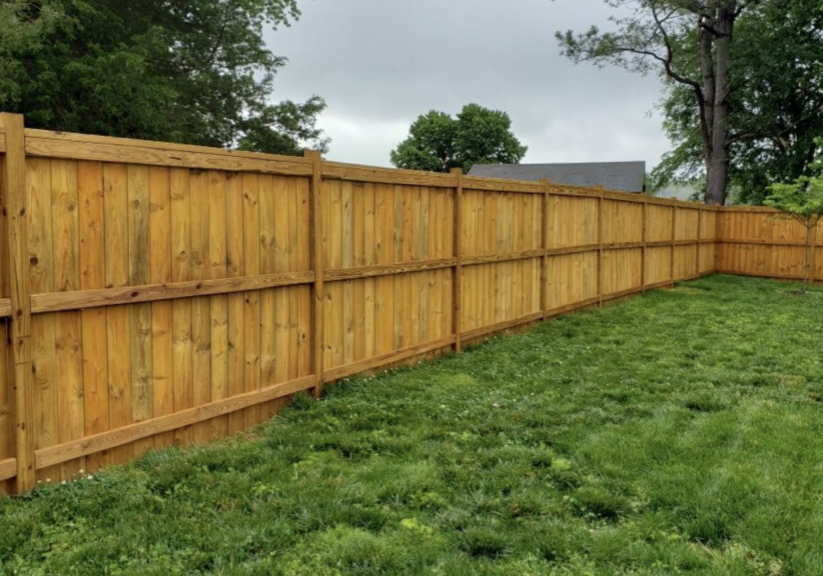 Freshly stained wooden fence by Paint EZ – professional deck and fence staining services that protect and enhance outdoor wood surfaces.