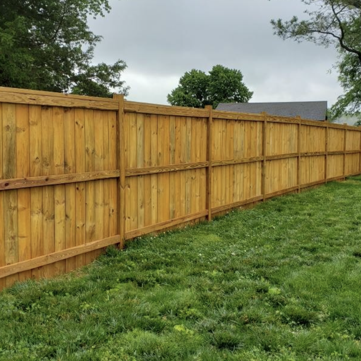 Freshly stained wooden fence by Paint EZ &ndash; professional deck and fence staining services that protect and enhance outdoor wood surfaces.