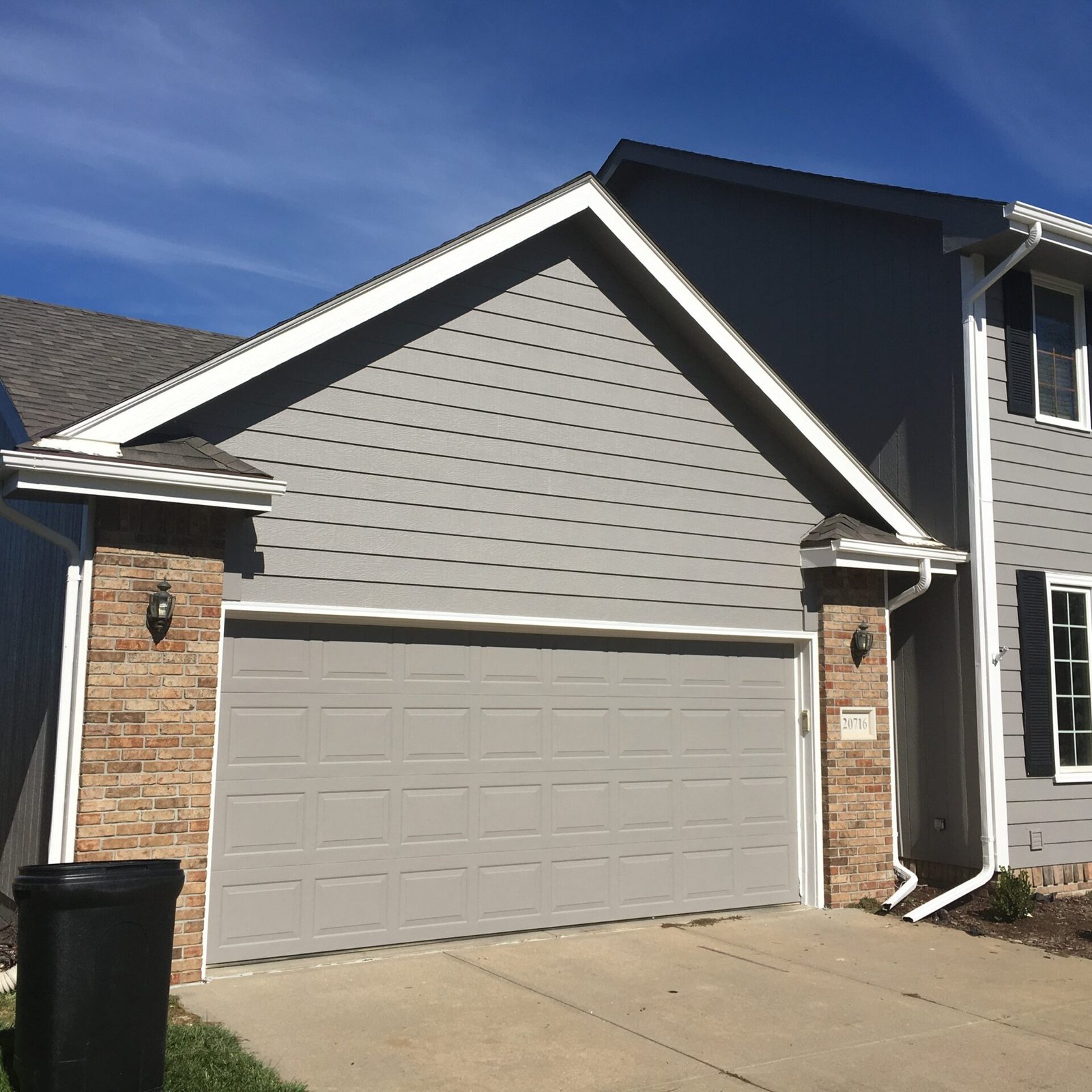 Paint EZ garage door painting project featuring a freshly painted gra garage door on a gray exterior home with clean trim and updated curb appeal.