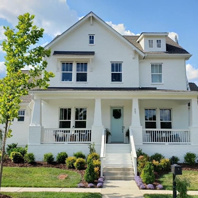 Brick home painted white with a light blue door.