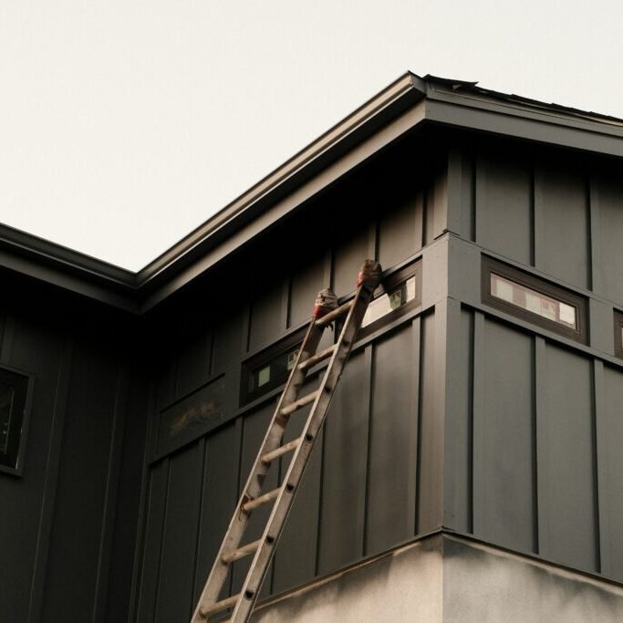 Ladder beside a partially painted exterior wall during an outdoor painting project.