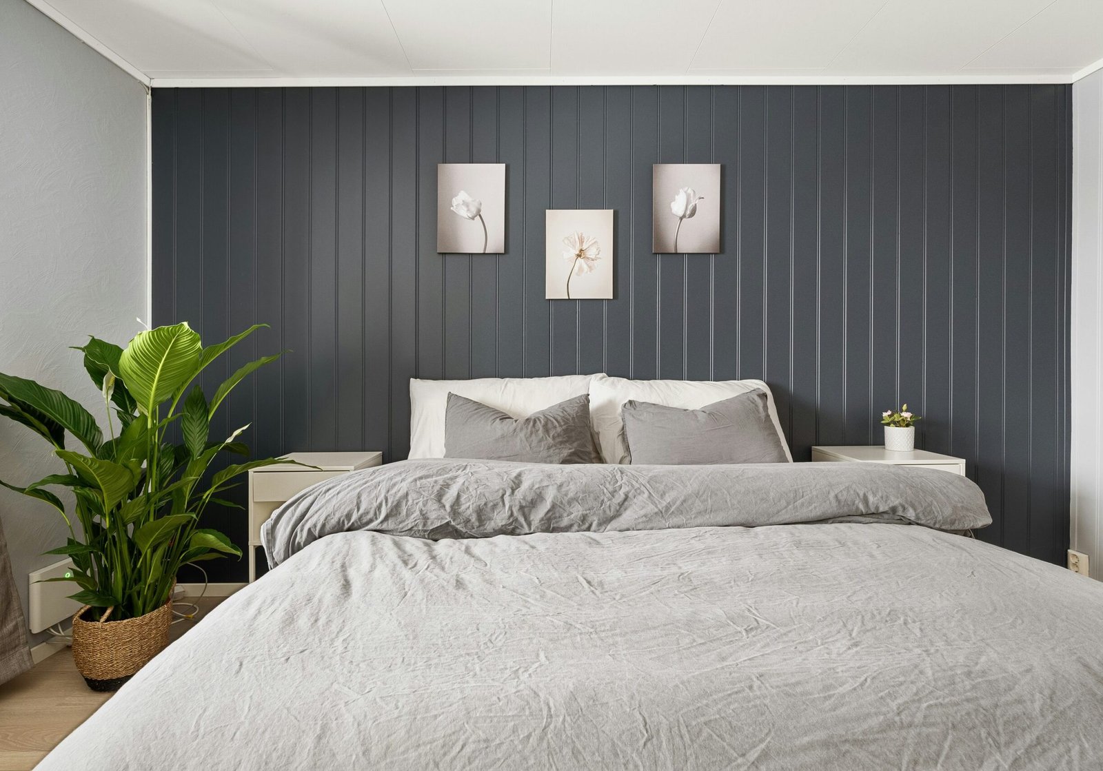Bedroom with a dark charcoal paneled accent wall, white ceiling, and neutral bedding