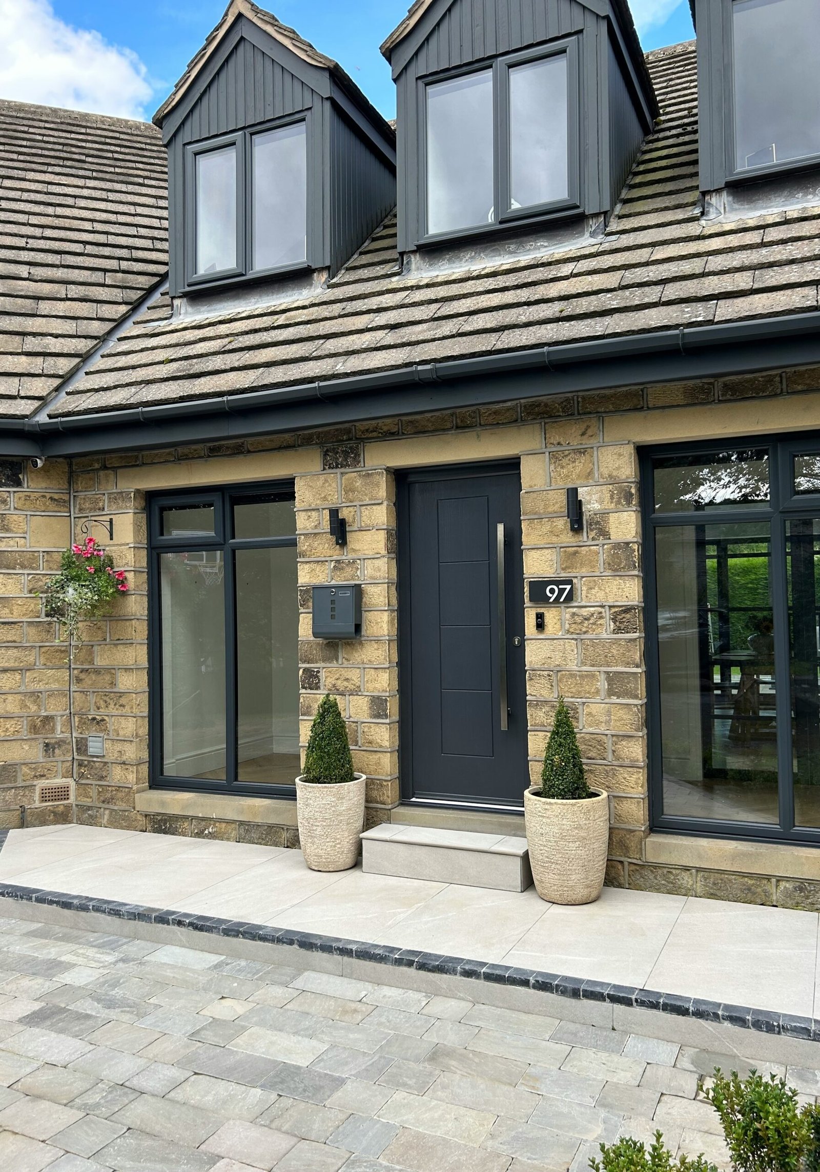 Gray stone house with a dark front door, white windows, and coordinated exterior finishes
