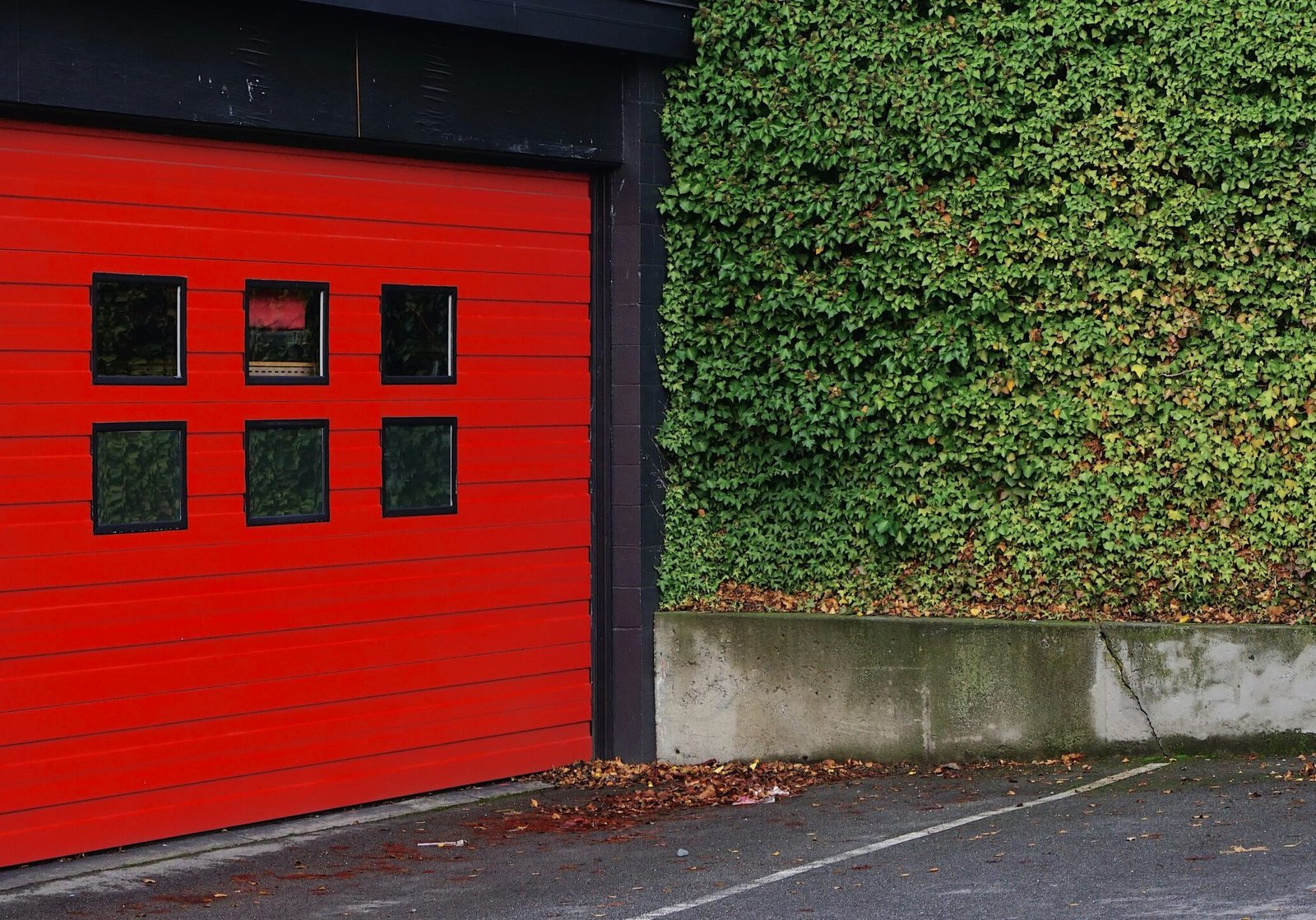 A building with steel garage doors painted red and black exterior siding.