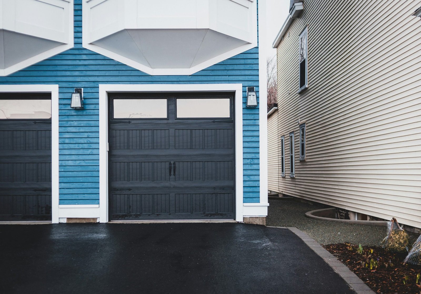 A two-story condo with fiberglass garage doors painted black and blue exterior siding.