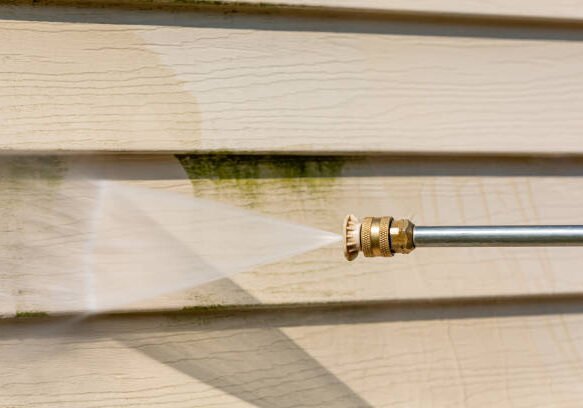 Exterior house siding being pressure washed before repainting