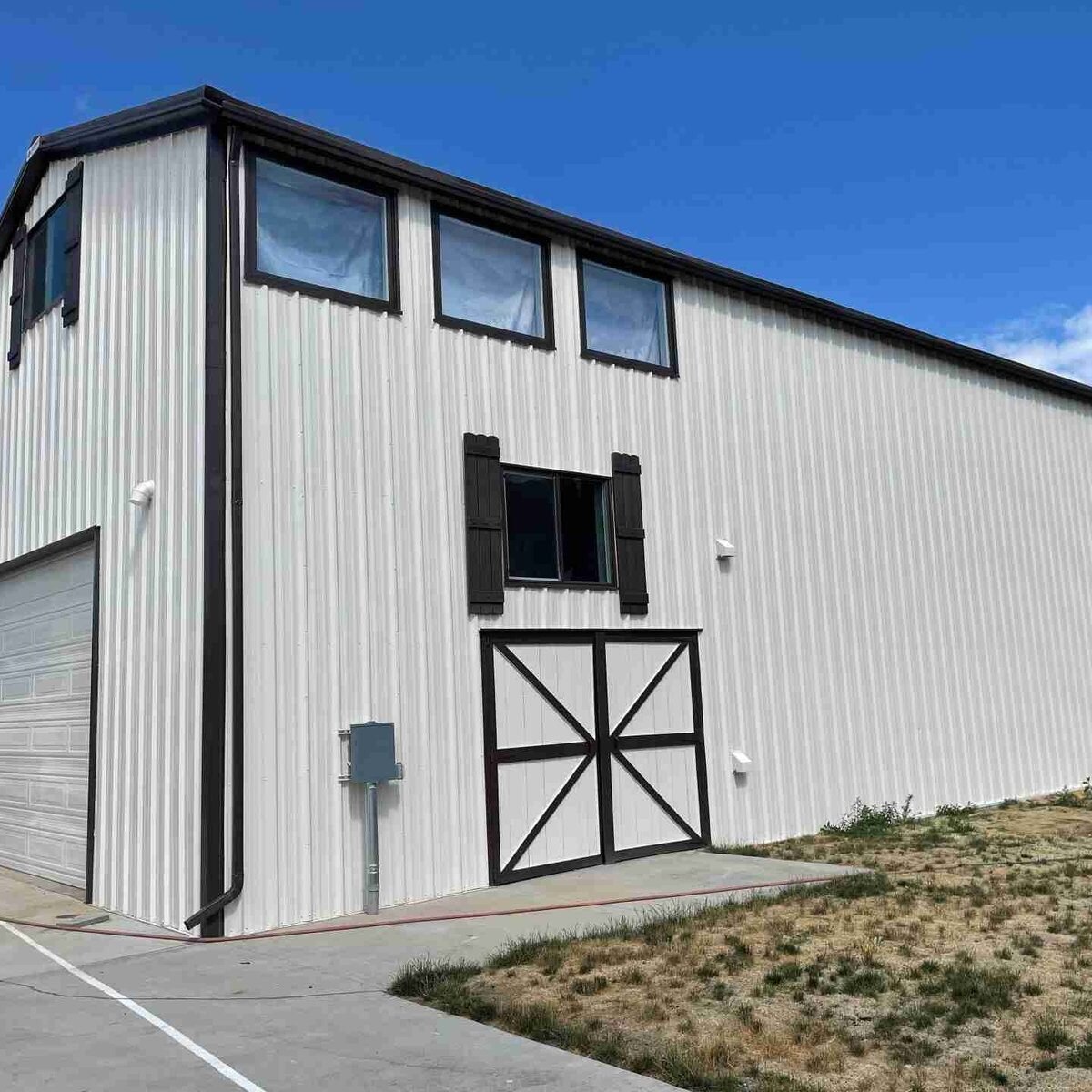 Modern metal barn with white painted siding and black trim showcasing clean exterior finish