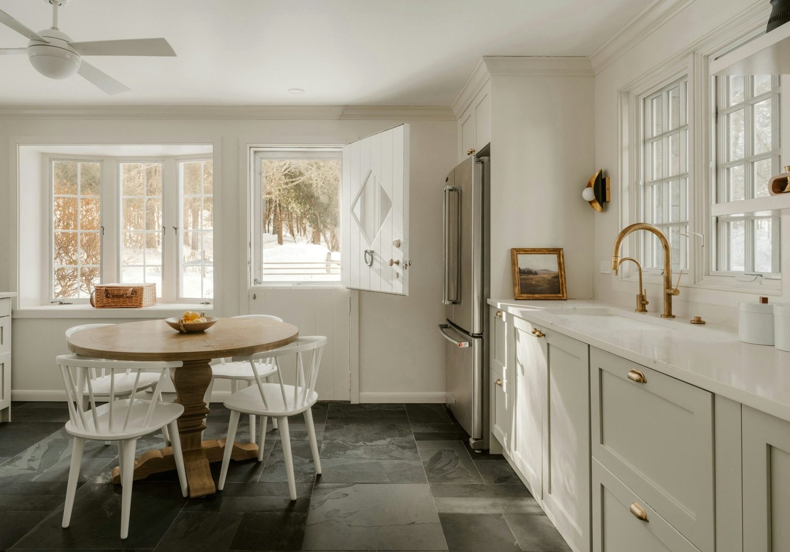Bright kitchen with light neutral walls, painted cabinets, white trim, and large windows