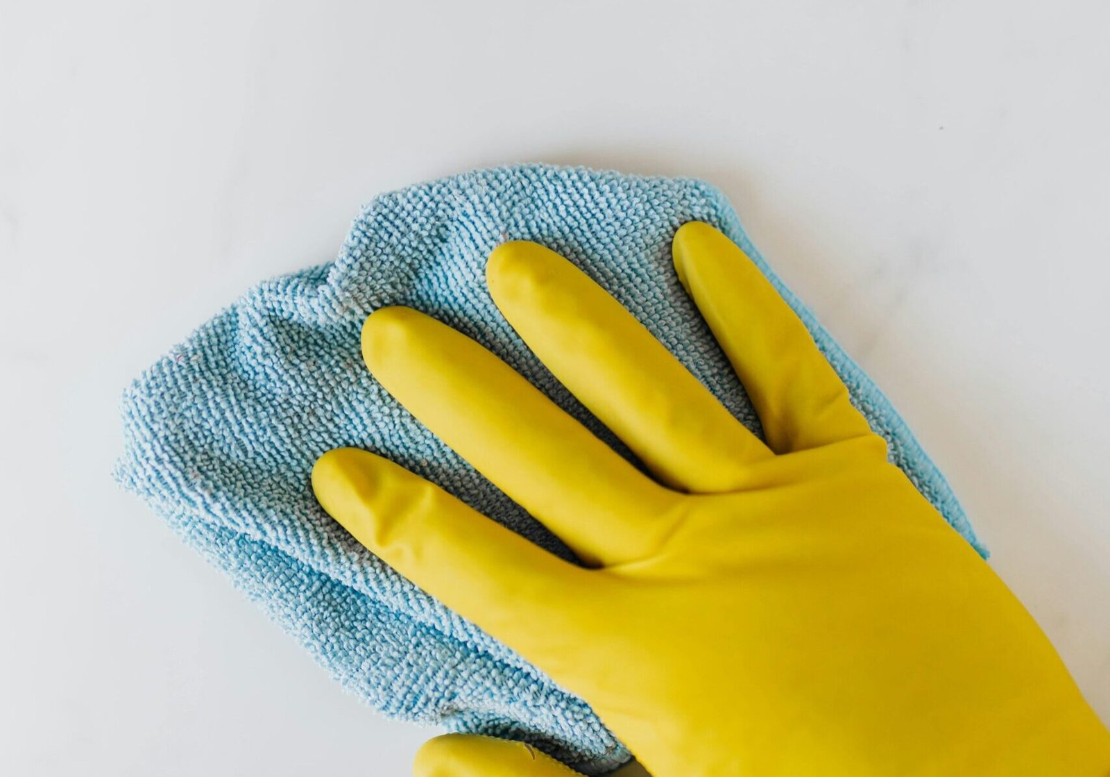 homeowner hand with rubber gloves on wiping interior painted wall.