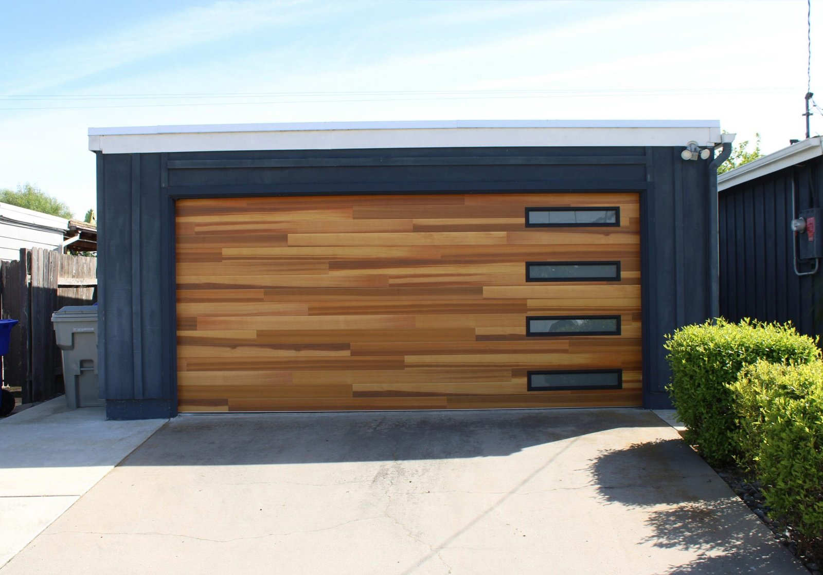 A building with wood garage doors stained and black exterior siding.
