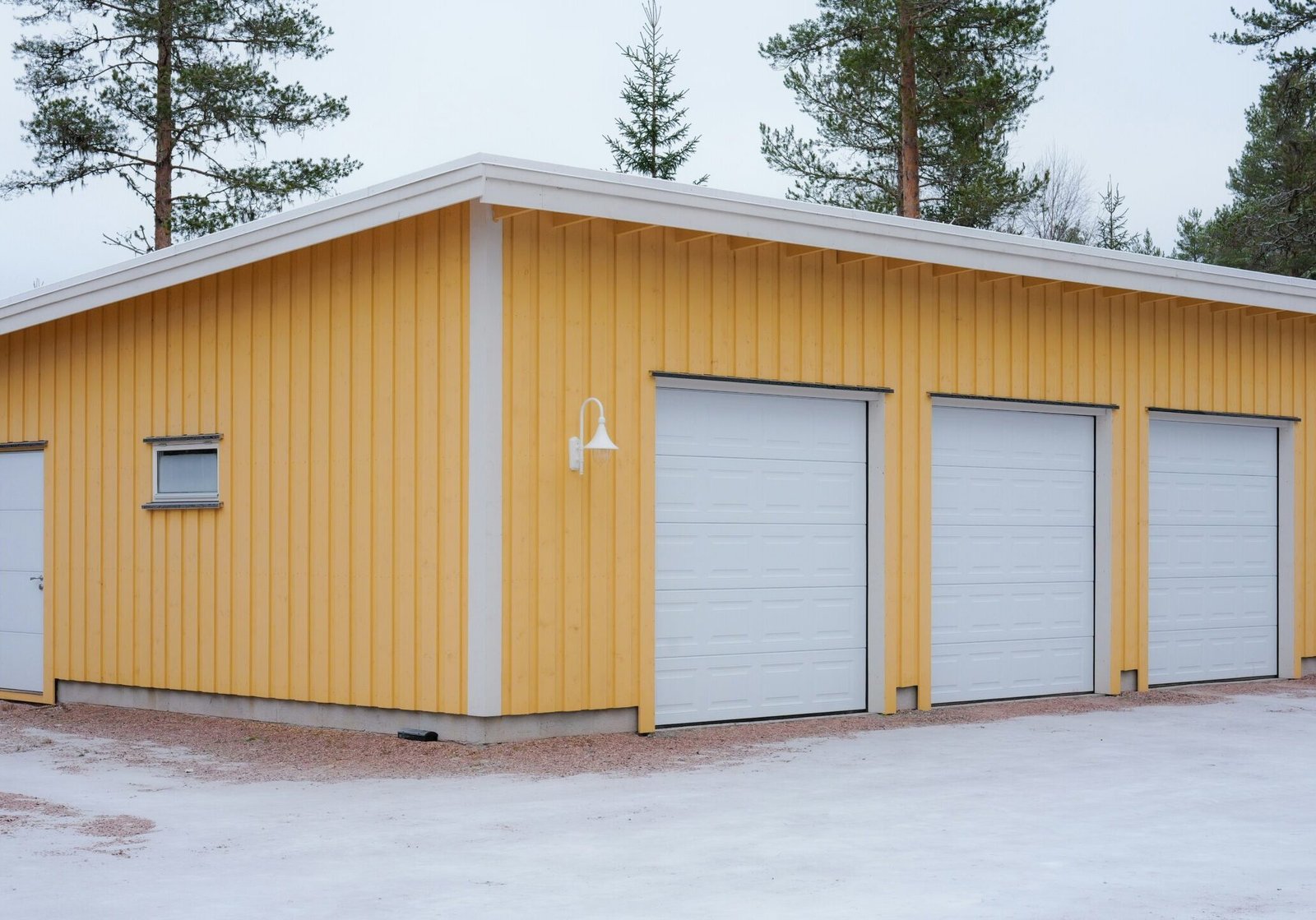 A building with aluminum garage doors painted white and yellow exterior siding.