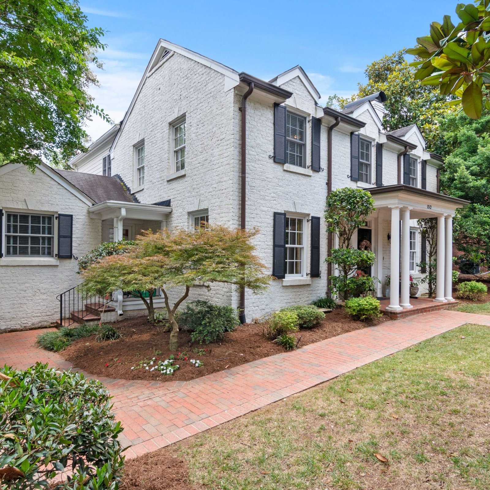 Whitewashed brick house exterior with black front door and dark wood porch columns