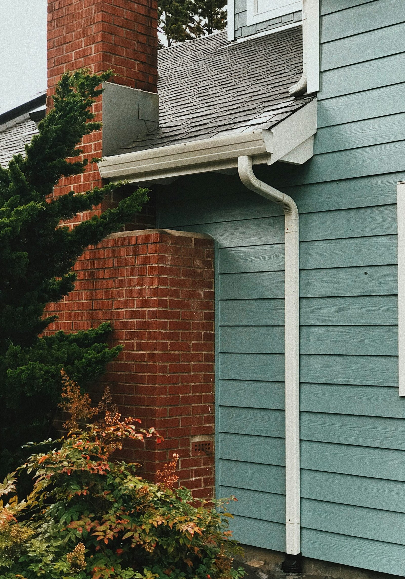Blue exterior siding coordinated with a red brick chimney and white trim